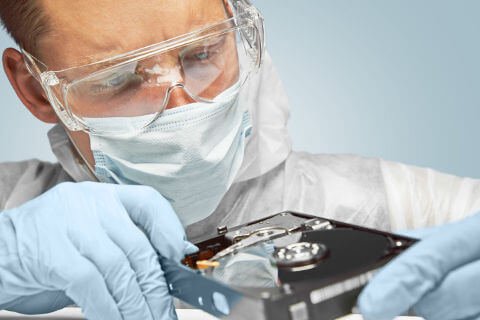 A laboratory worker examining a hard drive.