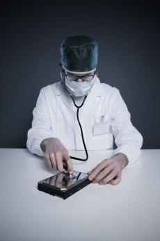 Doctor or Technician wearing a lab coat and stethoscope examining an hard disk