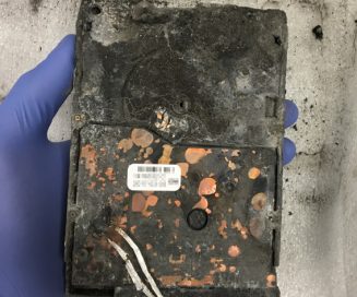 fire damaged drive held by gloved hand