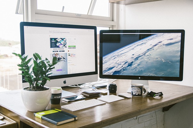 computer desk scene with screens and keyboard